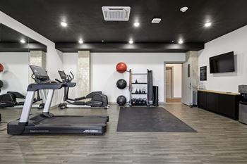 A gym with exercise equipment and a tv on the wall